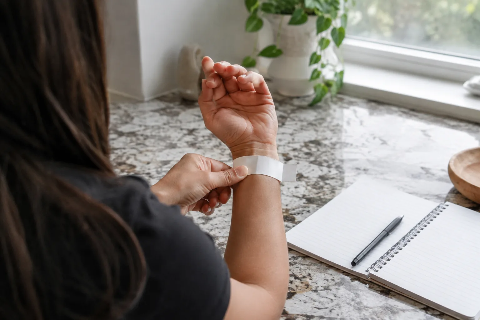 Hands measuring a wrist with a paper strip